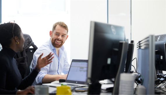 2 colleagues in conversation at desk