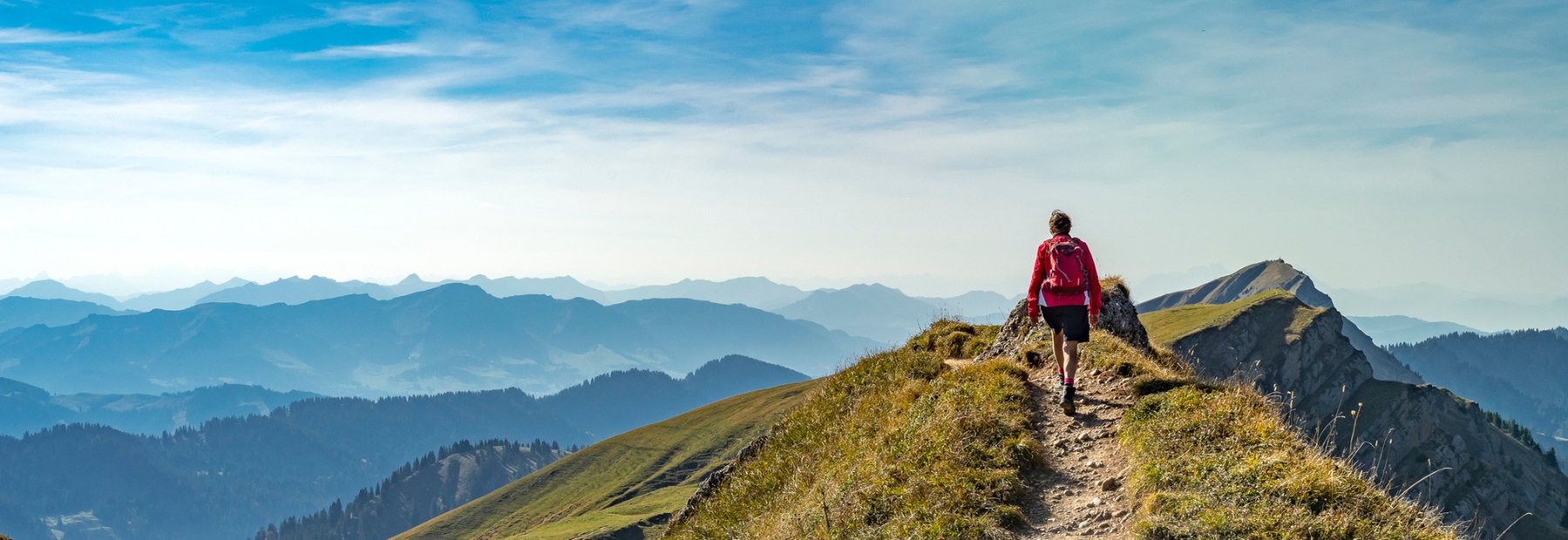 Person who has hiked to top of hill. Landscape in background.