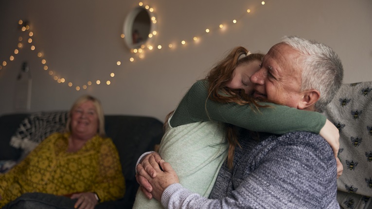 Granddaughter and Granddad hugging in living room