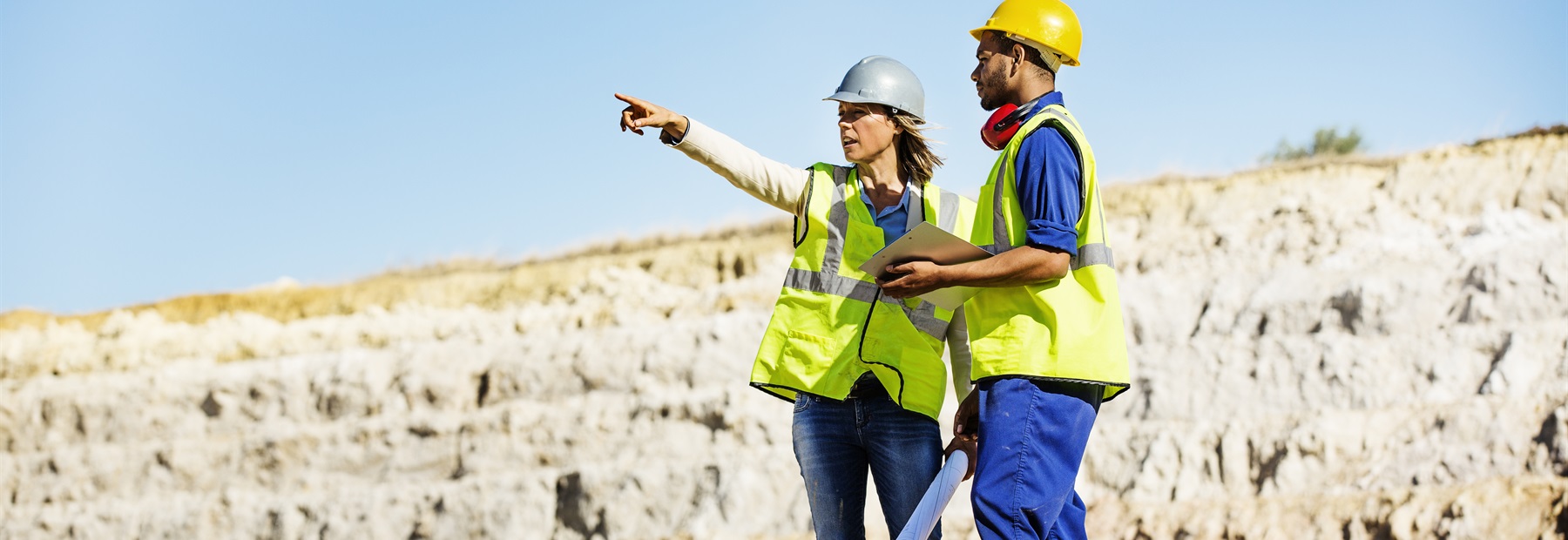 Two people in hard hats pointing